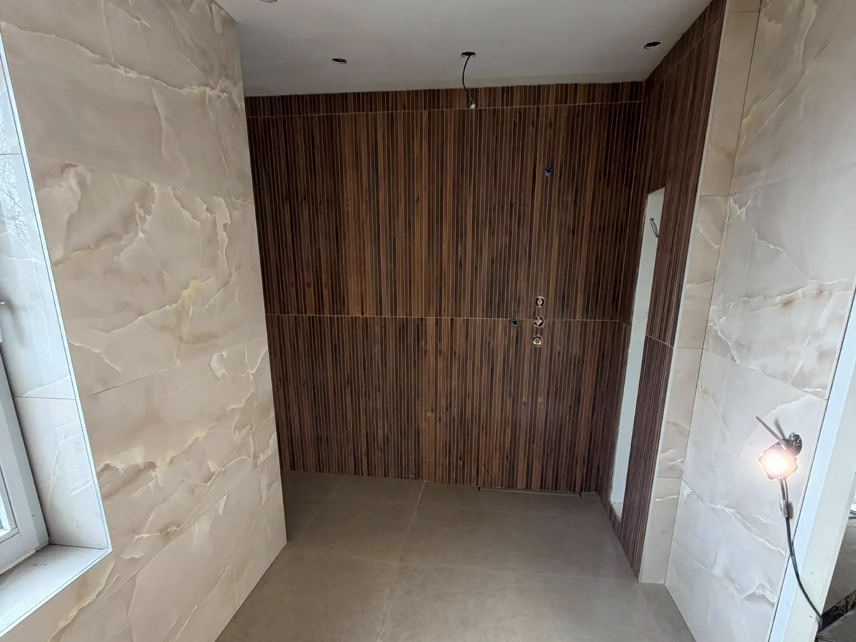 Badkamer in onyxlook platen met een wand in houten lamellen