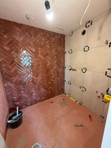 Doucheruimte met een wand in terracotta visgraattegels naast grootformaat wandtegels