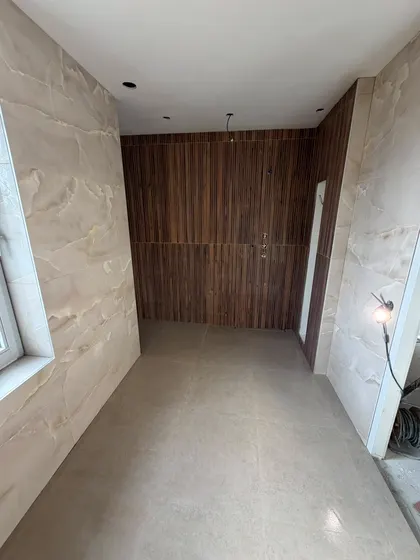 Badkamer in onyxlook platen met een wand in houten lamellen, de vloertegels liggen al